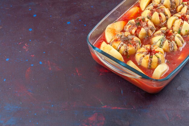 Half-top view cooked potatoes with sauce and minced meat on dark background.