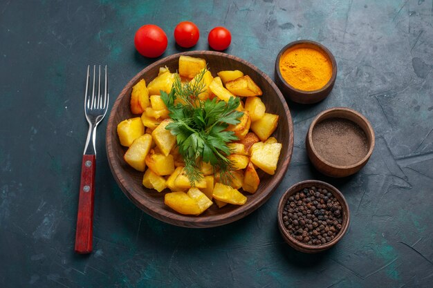 Half-top view cooked potatoes with seasonings on dark-blue surface