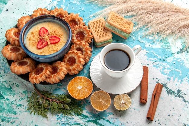 Half-top view delicious sugar cookies with waffles cup of coffee and strawberry dessert on the blue surface cookie biscuit sweet cake dessert color