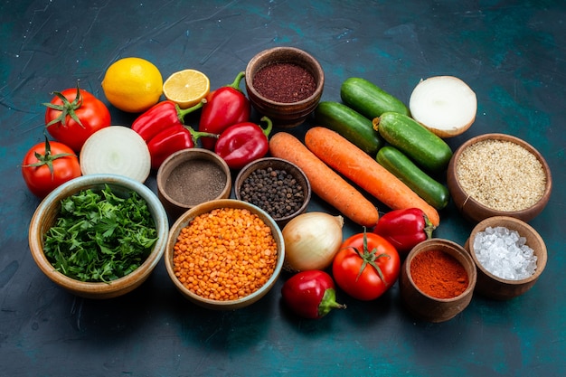 Free photo half-top view fresh vegetables with greens and seasonings on dark blue desk.