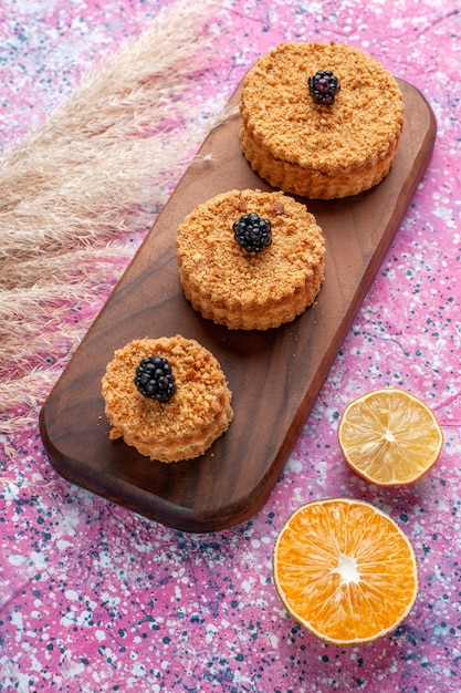 Half-top view of little delicious cakes on light-pink surface