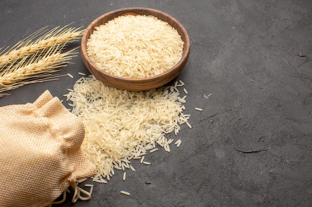 Half-top view of raw rice inside brown plate on dark-grey surface