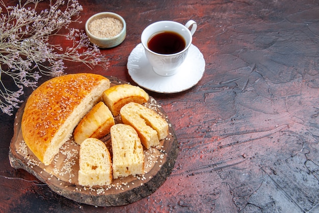 Half-top view tasty sweet pastry sliced in pieces with tea on dark background