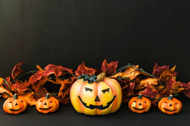 Halloween decoration with five pumpkins and autumn leaves