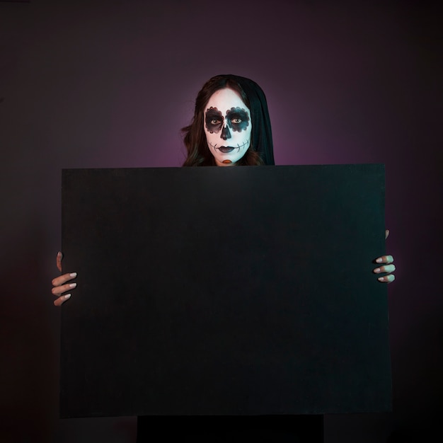 Free photo halloween girl with makeup holding big board