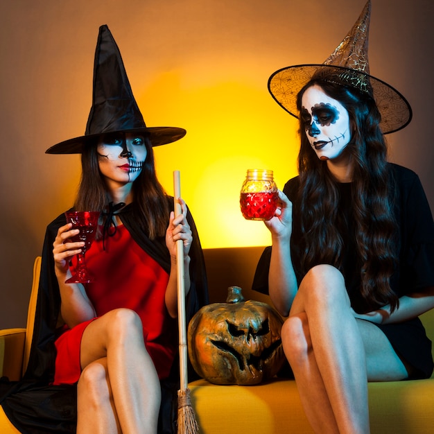 Free photo halloween girls on couch with pumpkin and drinks