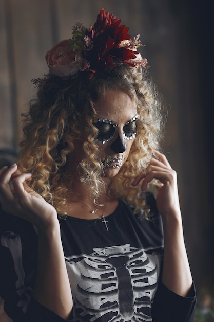 Halloween make-up skull beautiful woman with blond hairstyle. Santa Muerte model girl in black costume.