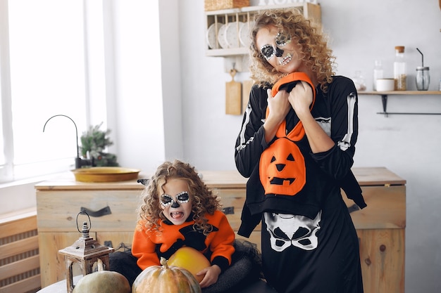 Free photo halloween. mother and daughter in mexican style halloween costume. family at home with pumpkins.