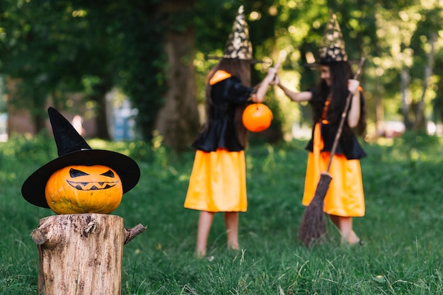 Halloween pumpkin on background of girls in witch costumes