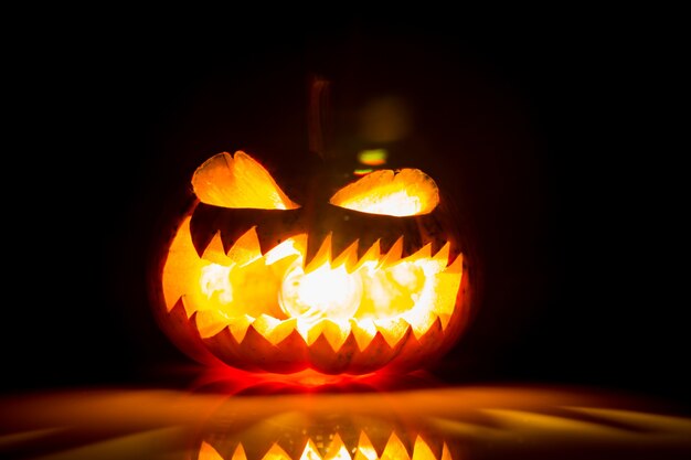 Halloween pumpkin with mouth open and with light inside and on a black background