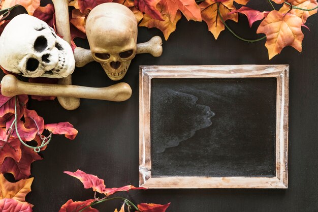 Halloween slate composition with skulls and autumn leaves