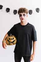 Free photo halloween teenager with vampire fangs and pumpkin