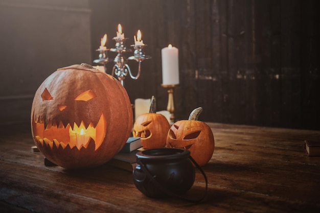 Free photo halloween traditional carved pumpkins, small boiler and candles on the wooden floor.