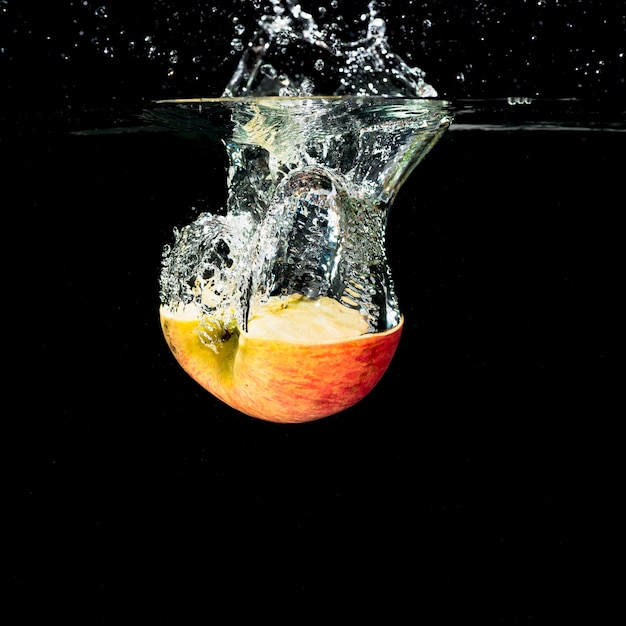 Free Photo halved apple with water splash on black background