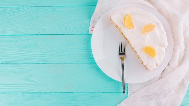 Free photo halved baked lemon cake with cheese spread and slices of citrus fruit on plate