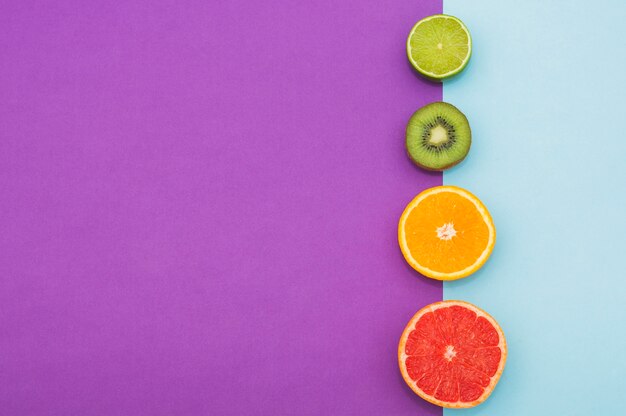 Halved citrus fruit; kiwi on the border of dual background