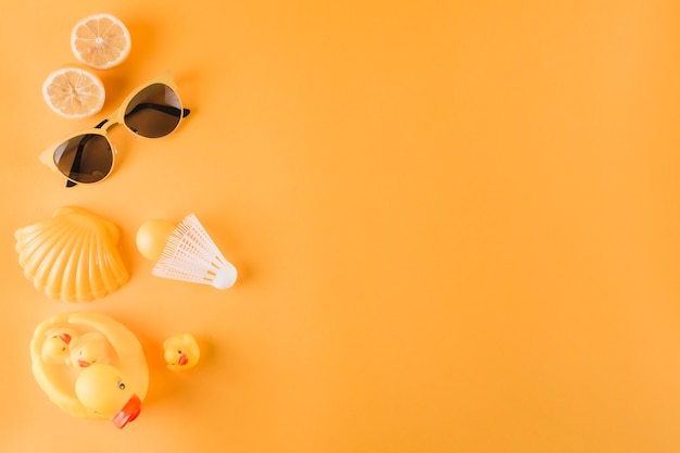 Free Photo halved oranges; sunglasses; plastic ball; shuttlecock; scallop and rubber duck on colored background