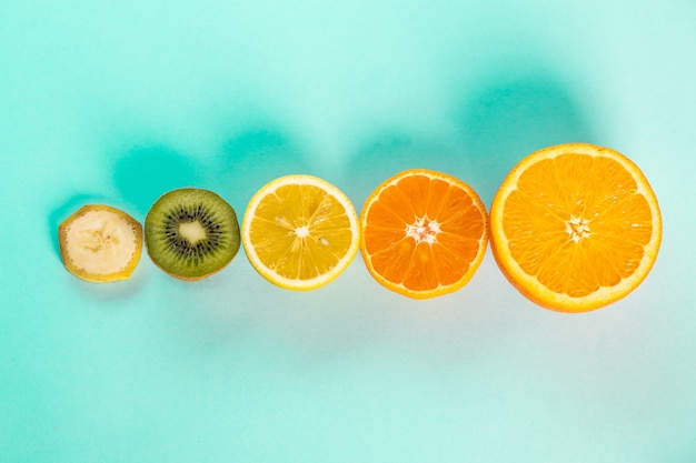 Free photo halves of oranges bananas kiwi and lemons on a blue table