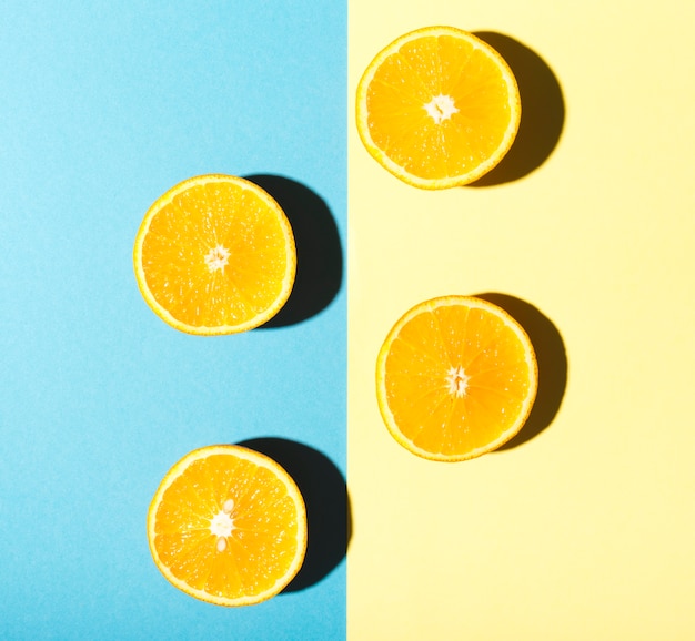 Free photo halves of oranges on blue and yellow background