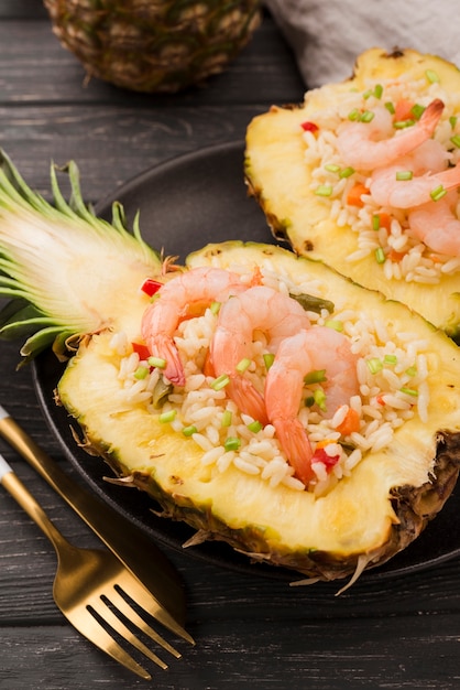 Free photo halves of pineapple with shrimps and golden cutlery