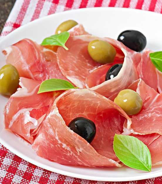 Free photo ham, olives, basil on old wooden