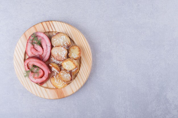 Ham rolls and fried potatoes on wooden plate. 