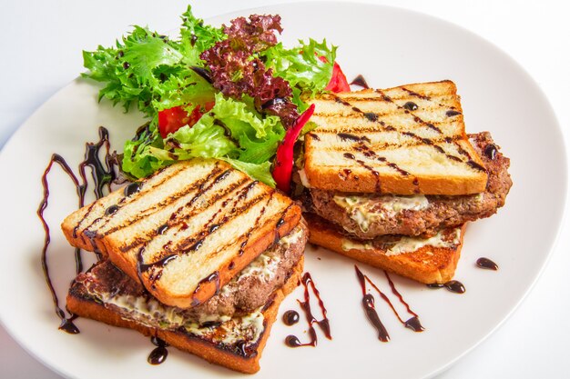 Hamburger closeup with bacon and cheese sauce, salad, olive dressing