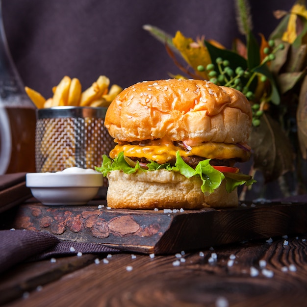 Free Photo hamburger and french fries side view on a wood and black background with decorations