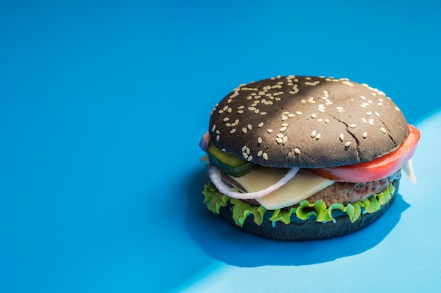 Free Photo hamburger with black bun on blue background