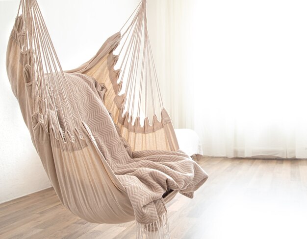 A hammock chair hangs in the room. Cozy place to relax at home.