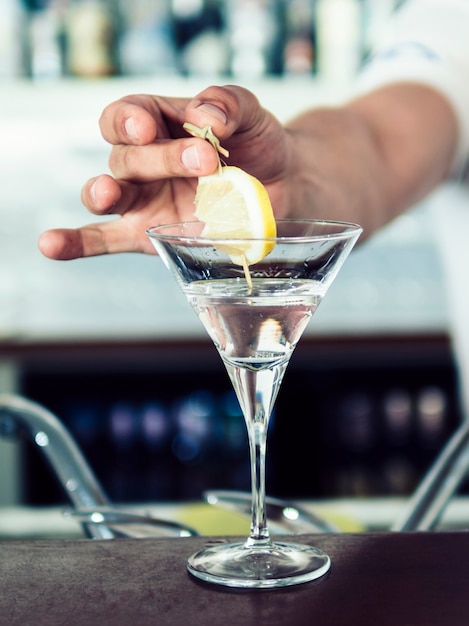 Free photo hand adding lemon in alcoholic cocktail