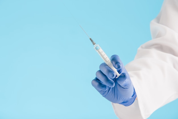 Free Photo hand in a blue glove holding syringe on blue