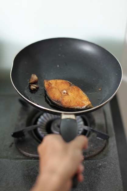 Free Photo hand cooking fish in a frying pan