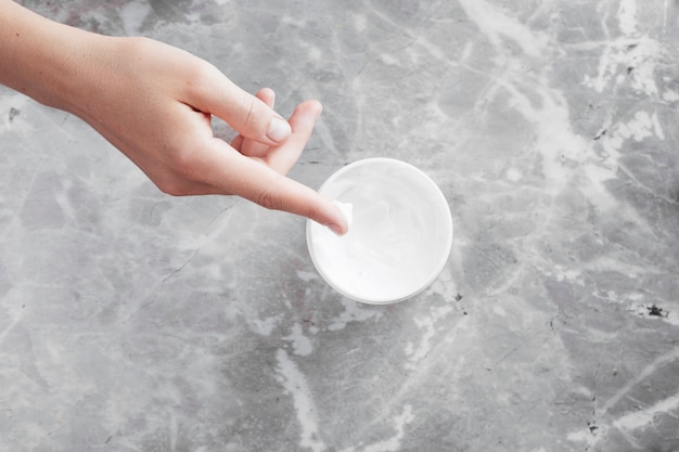 Hand and cream background top view