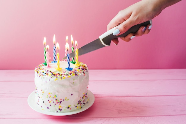 Hand cutting cake with candles