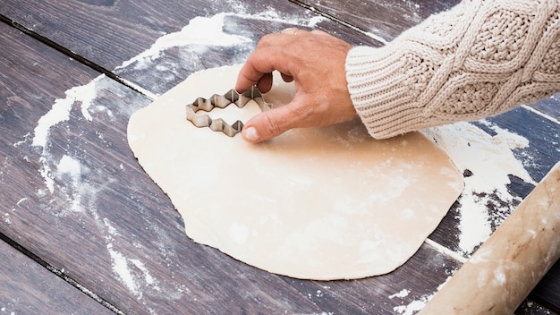 Free photo hand cutting christmas tree shaped cookies