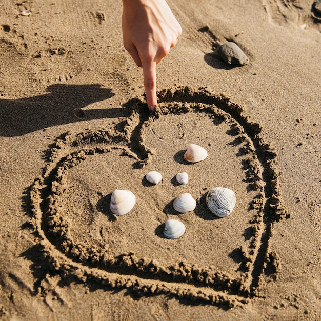 Free photo hand drawing heart in the sand