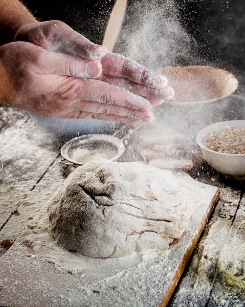 Free photo hand dusting with flour on dough over the table