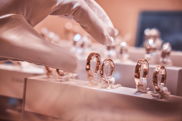 Free photo hand in gloves takes to exclusive rings on the showcase of a luxury jewelry store