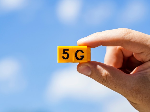 Free photo hand holding 5g snap cubes against sky with clouds