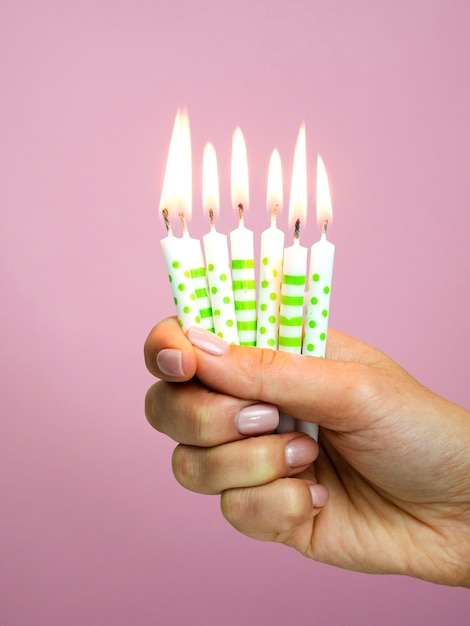 Hand holding birthday candles on pink background