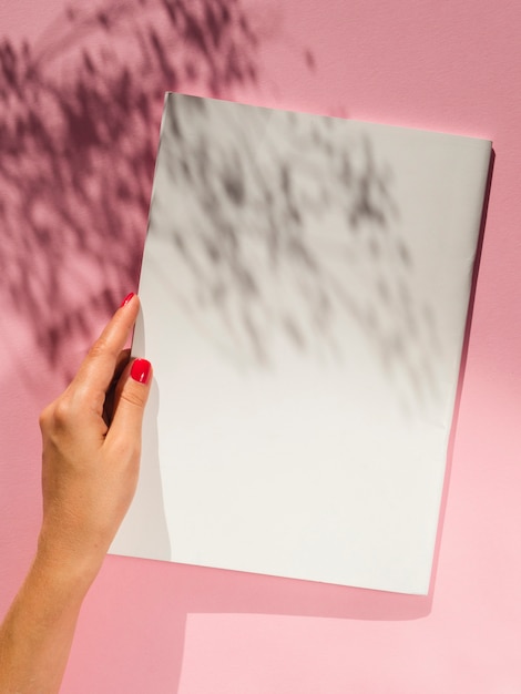 Free photo hand holding blank paper with shadows