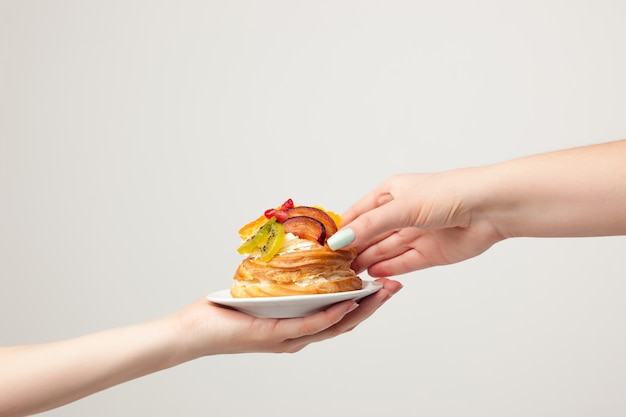 hand holding cake with fresh fruits on gray