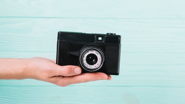 Hand holding camera in front of blue background