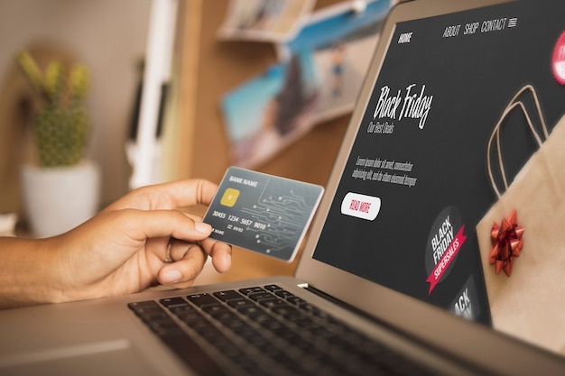 Hand holding a card next to a laptop mock up