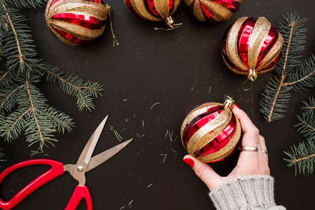 Hand holding Christmas bauble near fir twigs