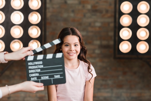 Hand holding clapper board in front of smiling girl