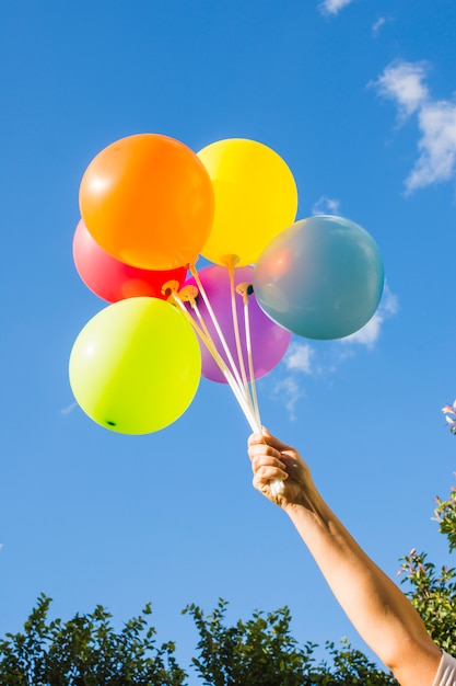 Hand holding collection of bright balloons