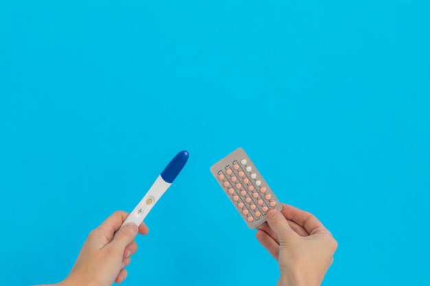 Hand holding contraceptive pills and and pregnancy test