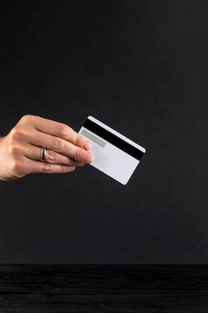 Free photo hand holding a credit card on black background